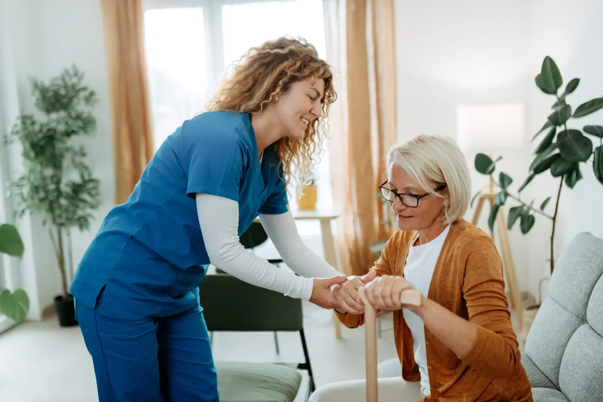 Caregiver assisting elderly woman with cane.