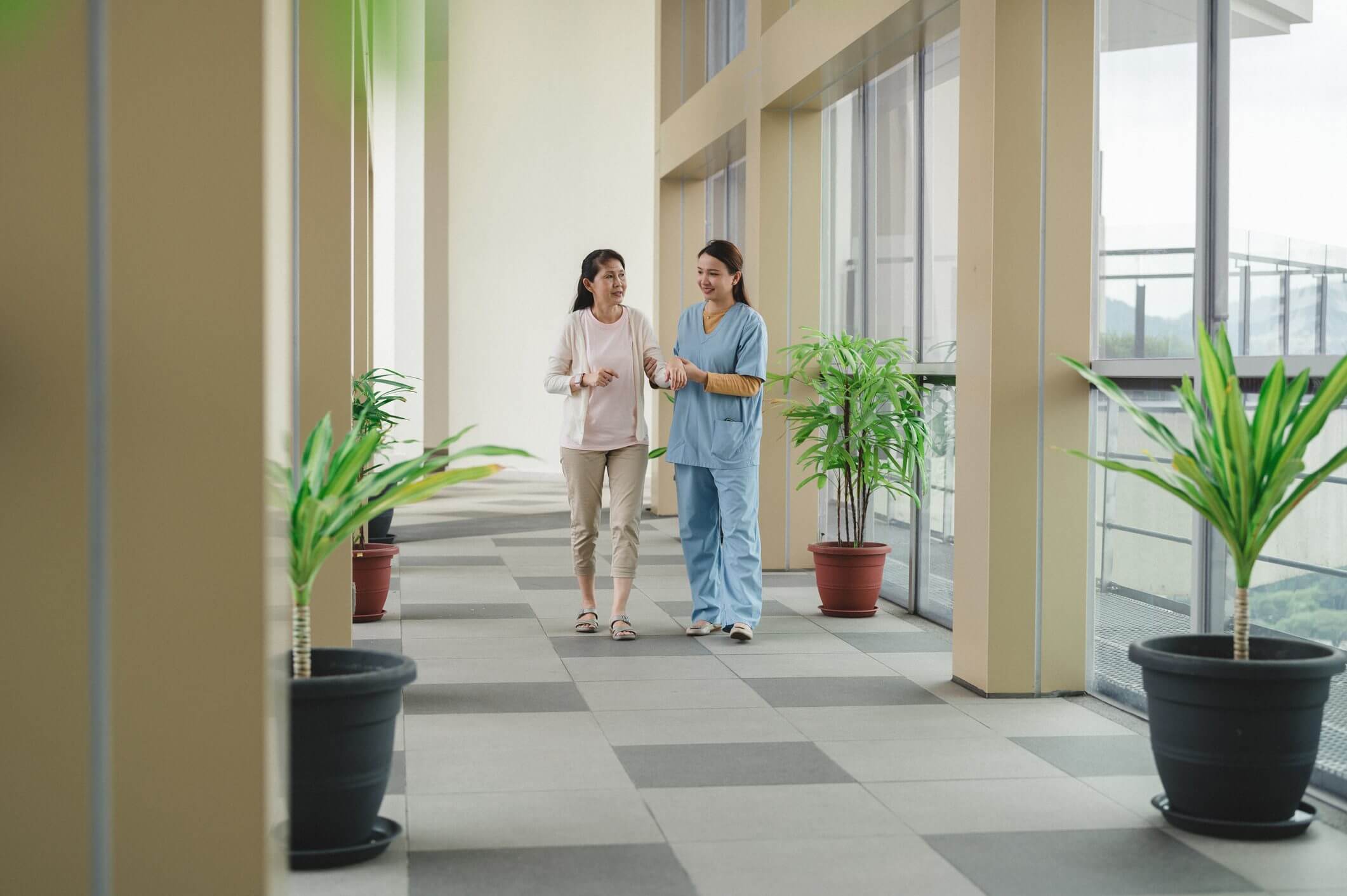 Two healthcare professionals walking and discussing in a hospital corridor.