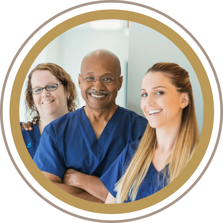 Three healthcare professionals smiling together in a hospital setting.