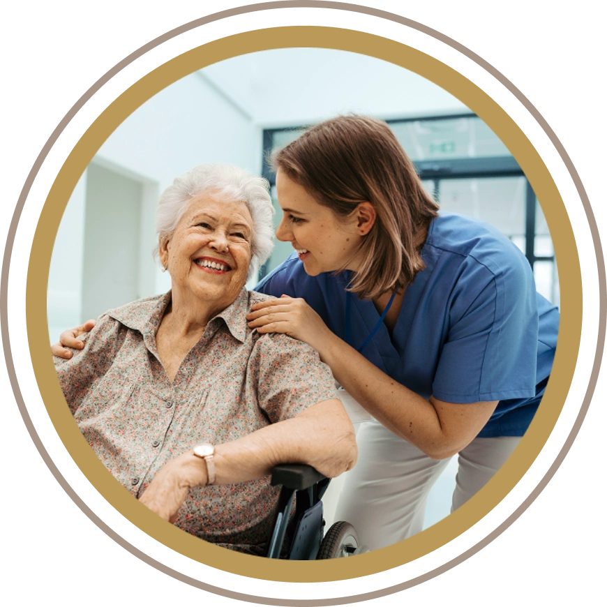 A caregiver warmly interacts with an elderly woman in a wheelchair.
