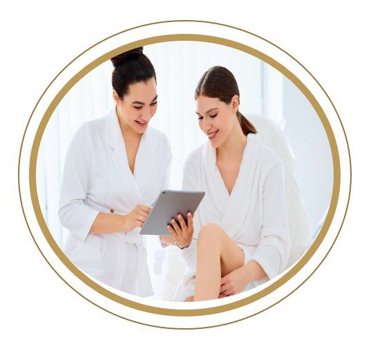 Two women in white robes sharing a moment with a tablet.